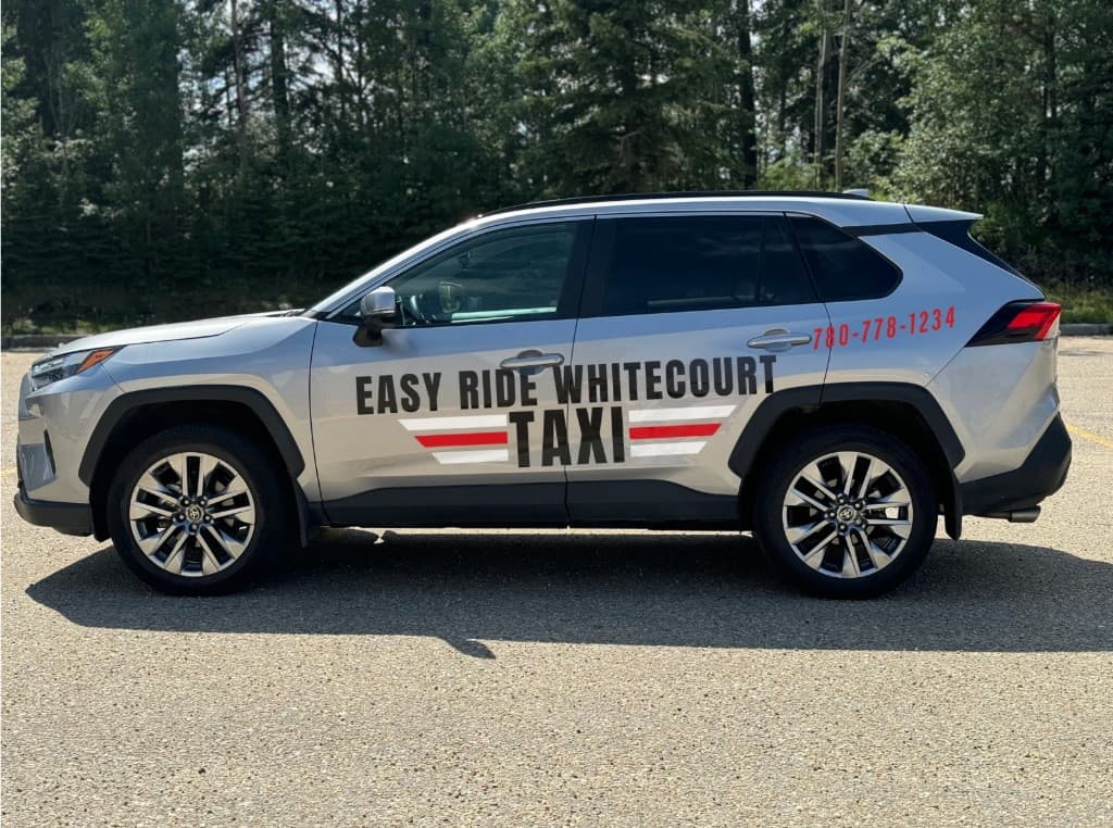 Side profile of a silver Easy Ride Whitecourt Taxi Toyota RAV4 with phone number (780) 778-1234, parked in front of a forest background.